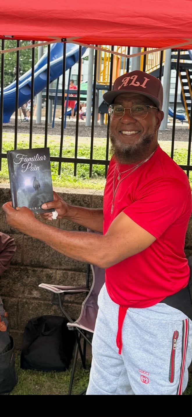 Abdur Ali holding a copy of Familiar Pain